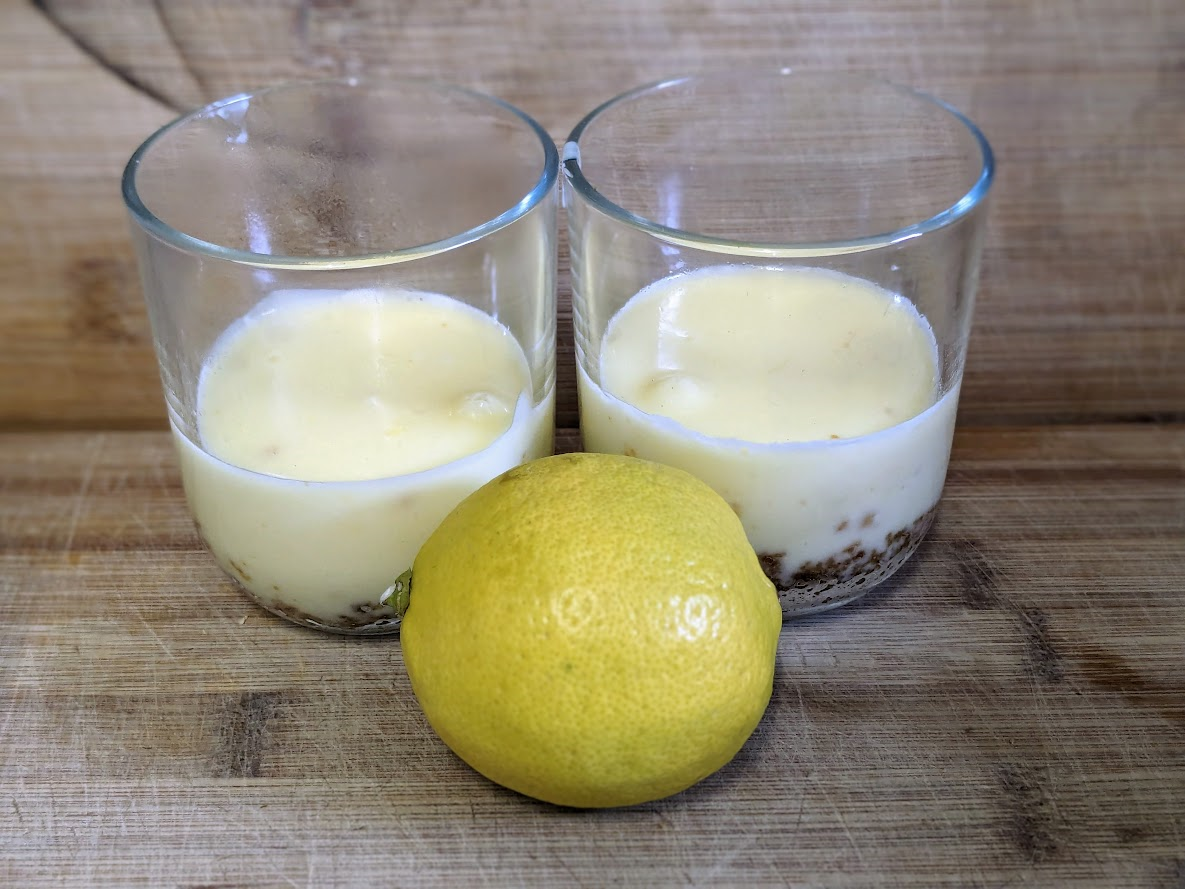 Picture of 2 Lemon Possets in glasses, next to a lemon.