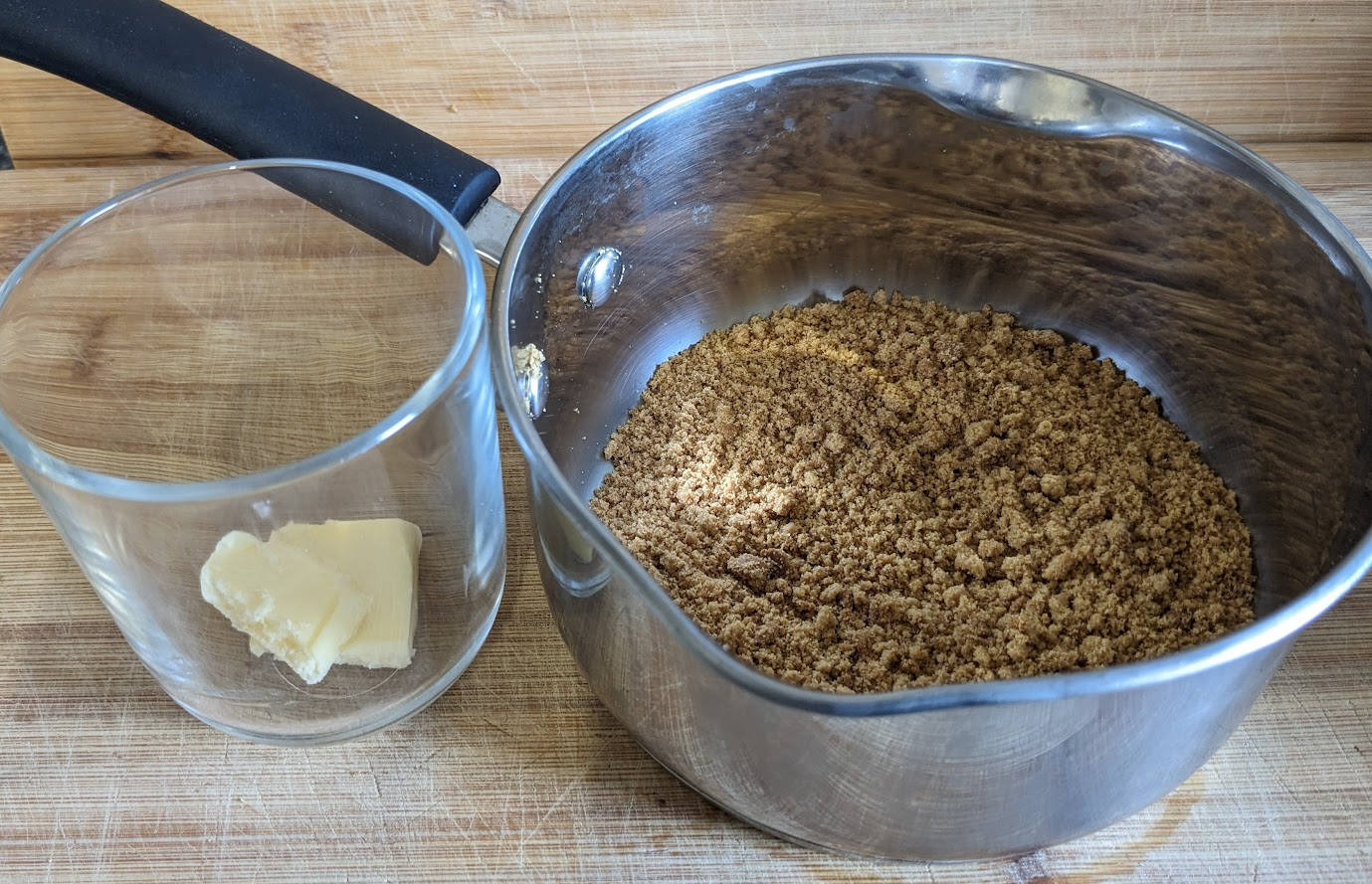 Picture of a pot of a knob of button in a glass, and a saucepan with broken gingernut biscuits.